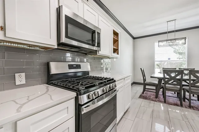 a kitchen with stainless steel appliances a white table and chairs