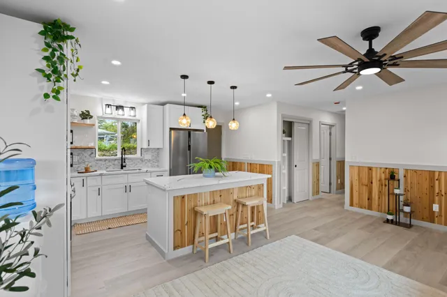 a kitchen with kitchen island a large counter top space appliances and a ceiling fan