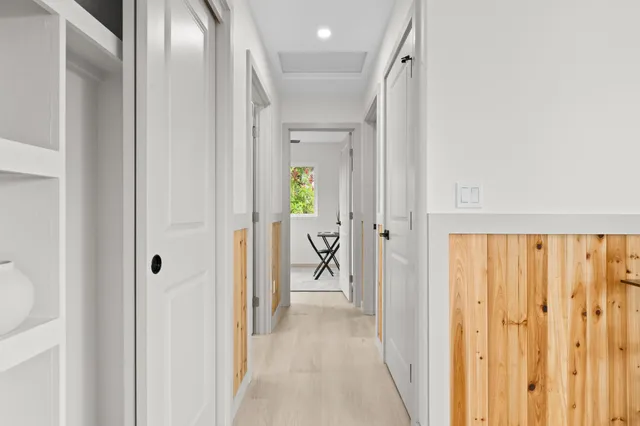 a view of a hallway with wooden floor windows and a bathroom