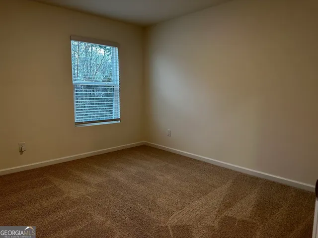an empty room with a chandelier fan and windows