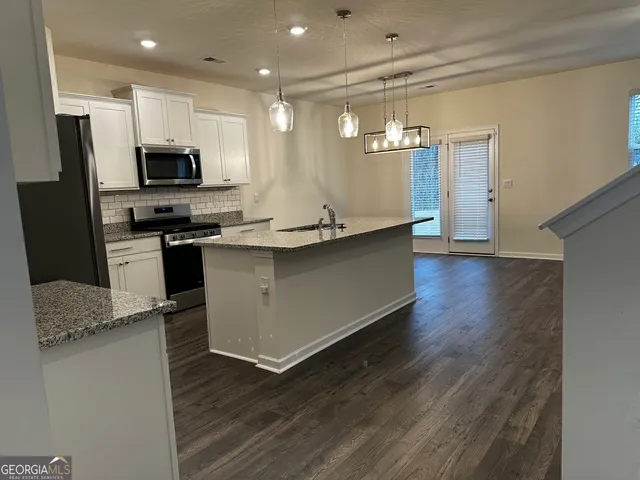 a kitchen with stainless steel appliances granite countertop a sink a stove and a refrigerator
