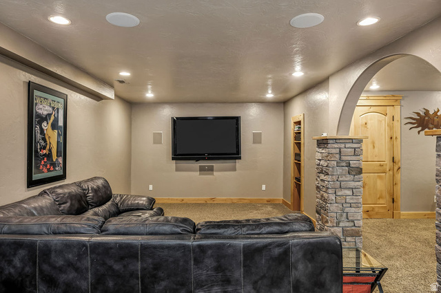 288 525 South Providence, UT 84332 - Photo 27 of 71 Entertainment room featuring recessed lighting, integrated ceiling speakers, a wall-mounted television, and an arched entry with stone-clad columns