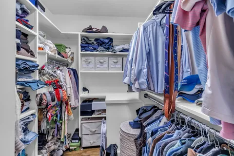 a view of walk in closet with clothes and shoes