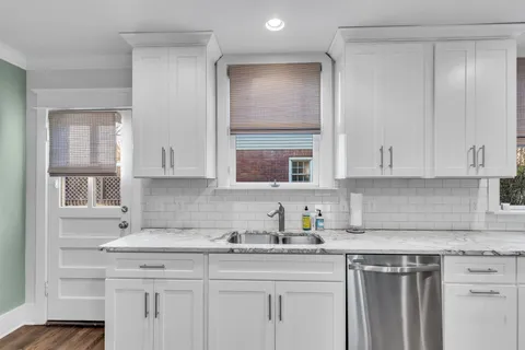 a kitchen with stainless steel appliances granite countertop a sink a stove and white cabinets