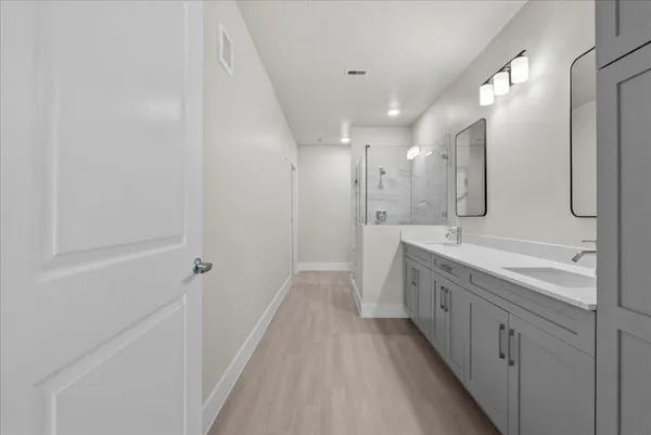 a bathroom with a double vanity sink and mirror with shower
