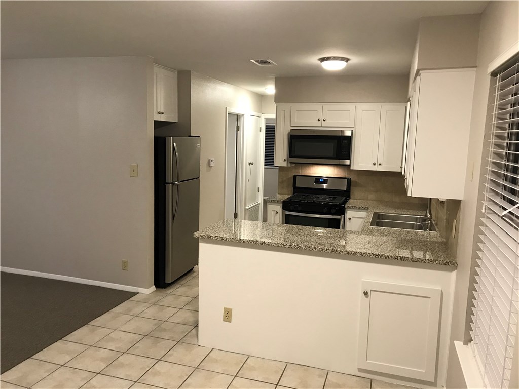 1810 Berkeley Avenue, Unit B Austin, TX 78745 - Photo 6 of 9 Updated kitchen features SS appliances, granite counters with tile backsplash, and Shaker cabinet doors.