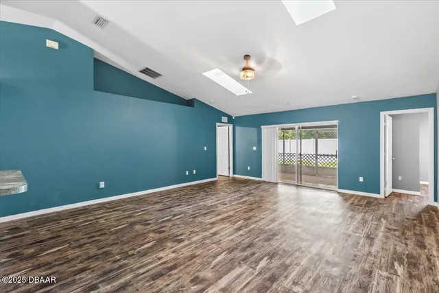 a view of an empty room with window and wooden floor