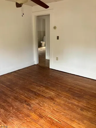 a view of a room with wooden floor and a ceiling fan