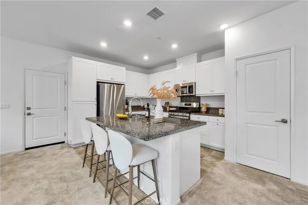 5584 Kate Way, Unit 10 Fontana, CA 92335 - Photo 6 of 42 a kitchen with stainless steel appliances a sink a stove a refrigerator cabinets and chairs