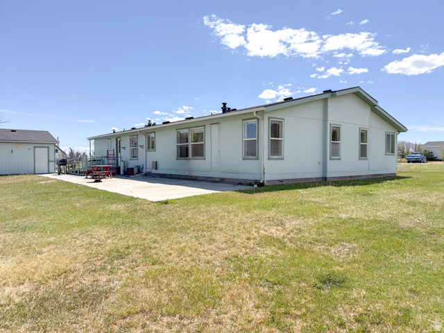 141 South 100 East Emery, UT 84522 - Photo 14 of 17 Expansive outdoor space featuring a large concrete patio, a freestanding shed structure, and a broad grassy area