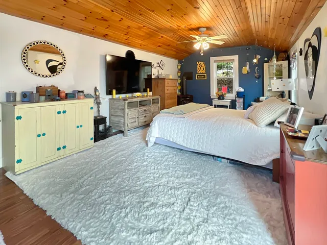 a spacious bedroom with a bed and a flat tv screen on dresser