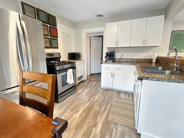 a kitchen with granite countertop a refrigerator stove top oven and sink