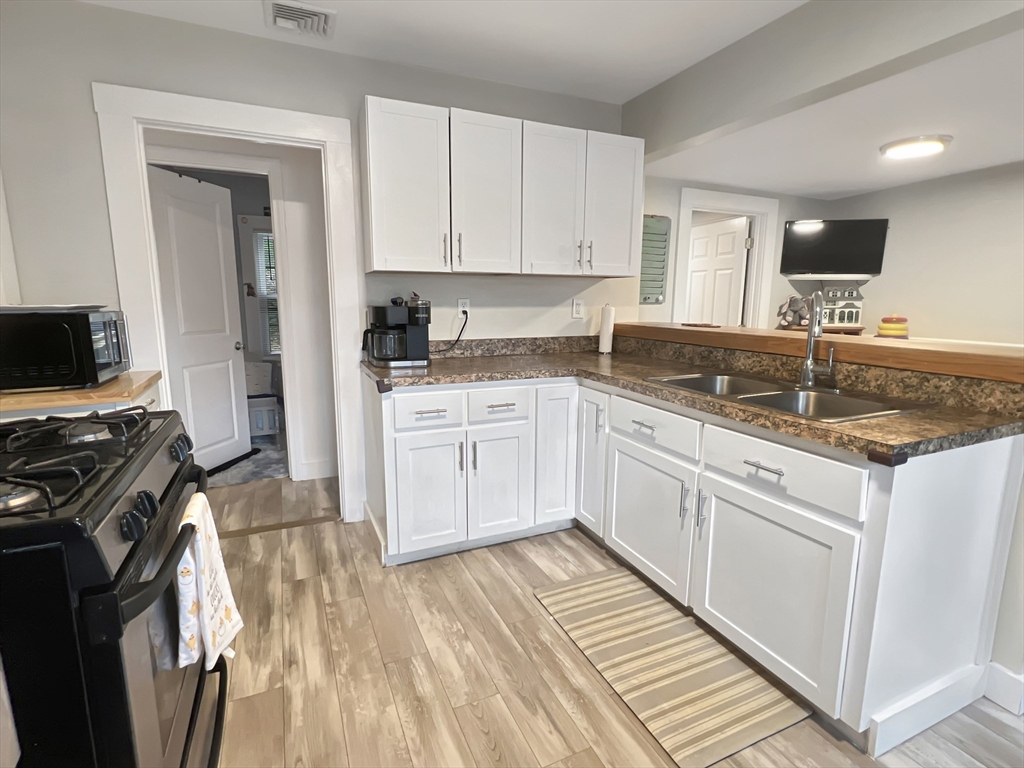 1649 Washington Street Canton, MA 02021 - Photo 4 of 38 a kitchen with a sink dishwasher a stove and white cabinets with wooden floor