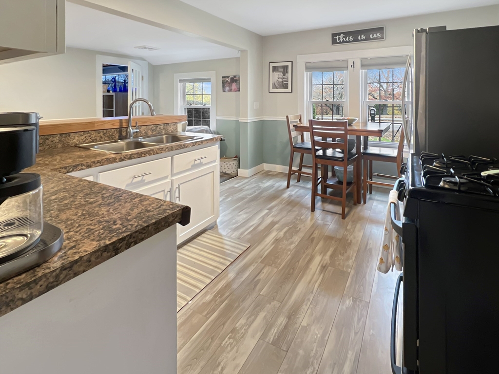 1649 Washington Street Canton, MA 02021 - Photo 5 of 38 a kitchen with stainless steel appliances granite countertop a stove top oven a dining table and chairs with wooden floor