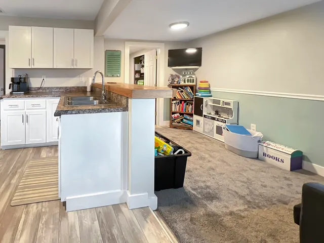 a living room with stainless steel appliances kitchen island granite countertop a refrigerator and a stove top oven