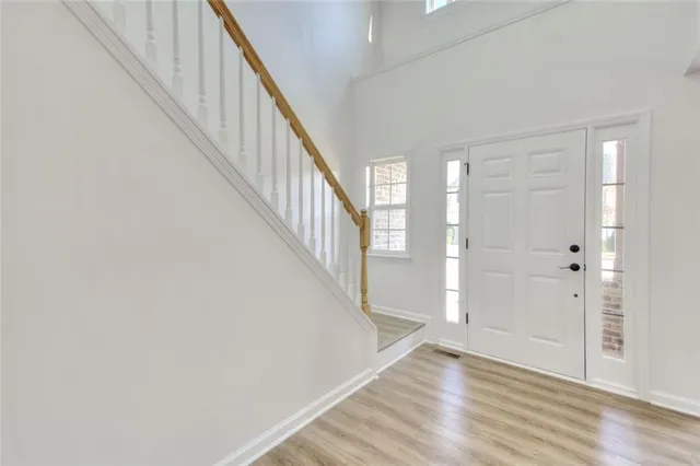 an empty room with windows a fireplace and wooden floor