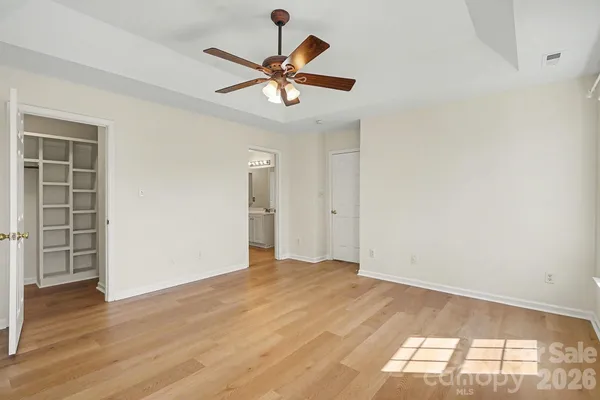an empty room with wooden floor fan and windows