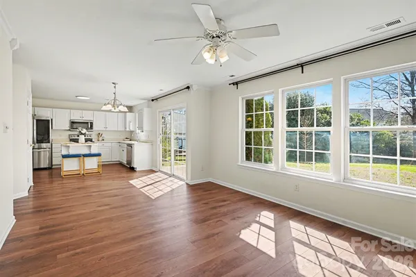 a view of an empty room with kitchen appliances and wooden floor