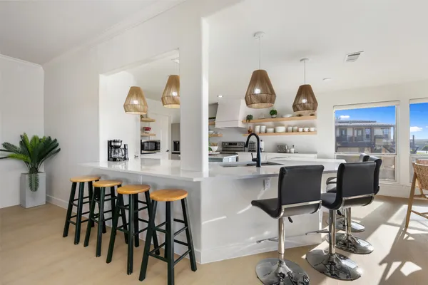 a kitchen with kitchen island a stove a sink a oven a dining table and chairs with wooden floor