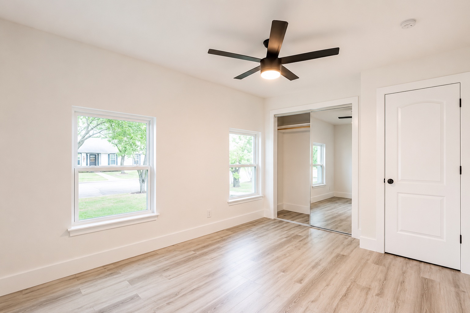 7500 Rio Pass Austin, TX 78724 - Photo 10 of 15 Smooth wood-look flooring and multiple windows create a serene, well-lit modern bedroom.