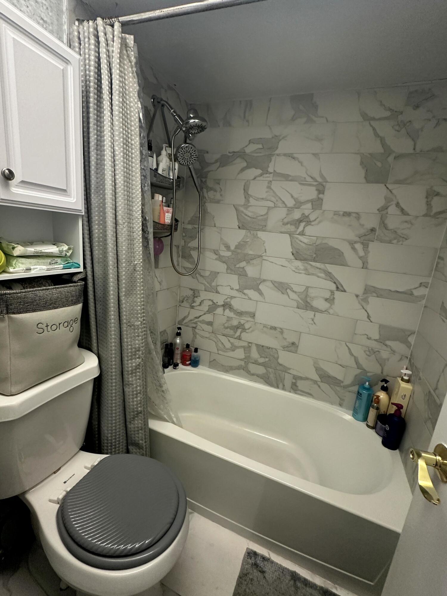 2500 Fiore Way, Unit 102C Delray Beach, FL 33445 - Photo 20 of 33 a white toilet and tub sitting next to a bathroom sink