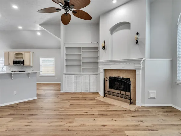 a view of an empty room with a fireplace and wooden floor