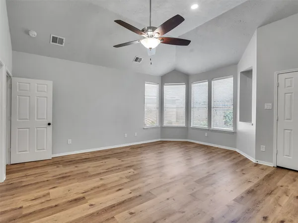 a view of an empty room with window and wooden floor