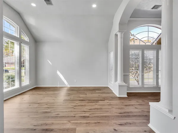an empty room with wooden floor and windows