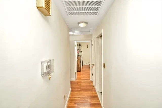 a view of a hallway with wooden floor and a bathroom