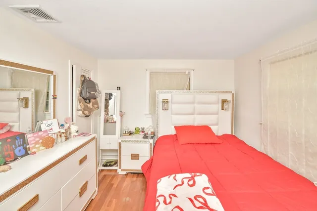 a bedroom with a bed and a large mirror on the dresser