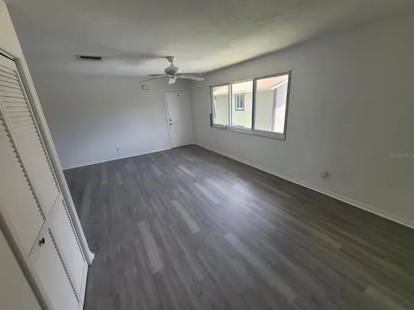 an empty room with wooden floor and windows