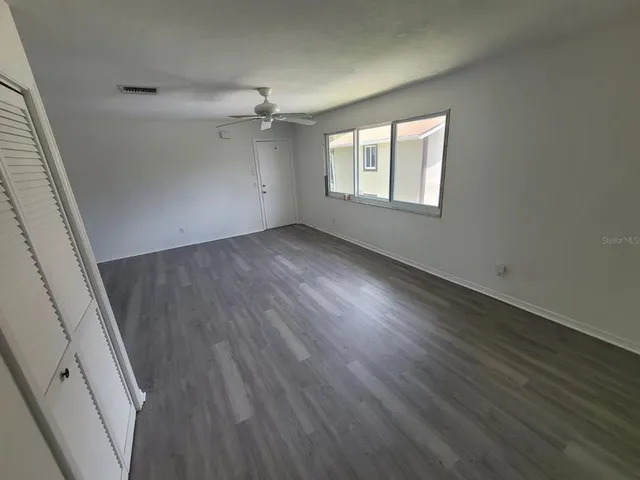 an empty room with wooden floor and windows