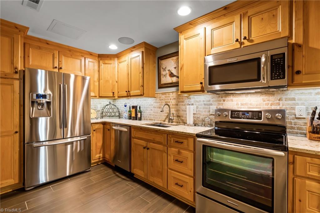 11555 Double Spring Road Lewisville, NC 27023 - Photo 32 of 50 Lower level, fully equipped kitchen with quartz countertops, stainless appliances, tiled backsplash and beautiful cabinetry