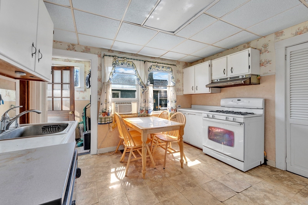151-153 Forest Street Arlington, MA 02474 - Photo 13 of 20 a kitchen with stainless steel appliances granite countertop a stove a refrigerator a sink dishwasher a dining table and chairs with wooden floor