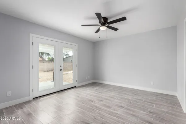 an empty room with wooden floor closet and windows