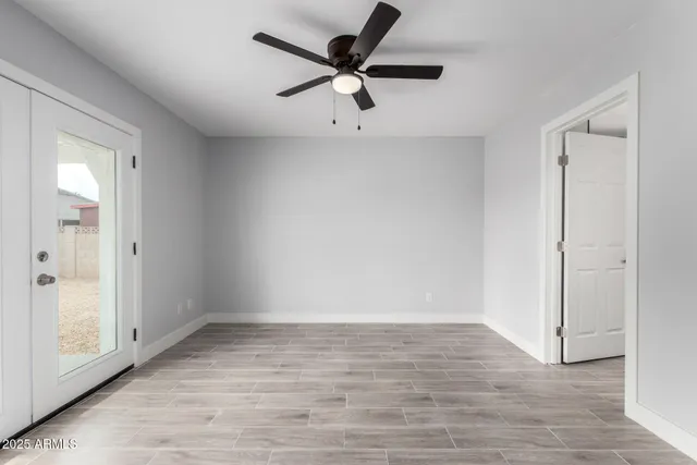 an empty room with wooden floor fan and windows