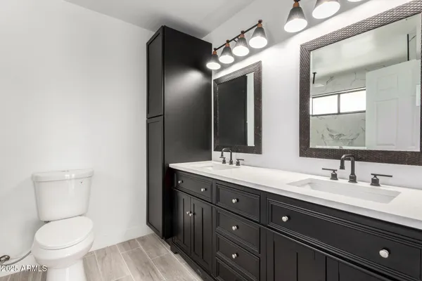 a bathroom with a toilet sink double vanity and mirror