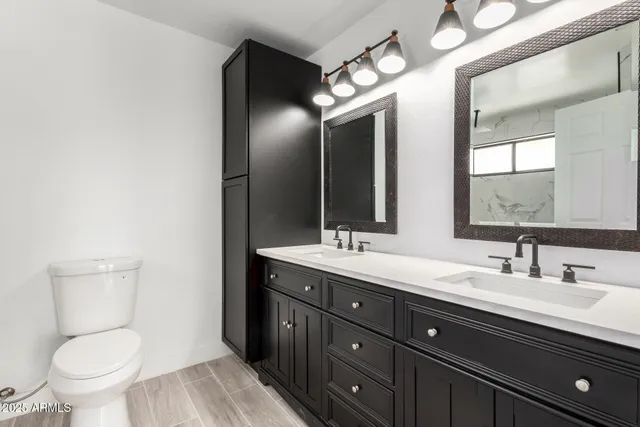 a bathroom with a toilet sink double vanity and mirror