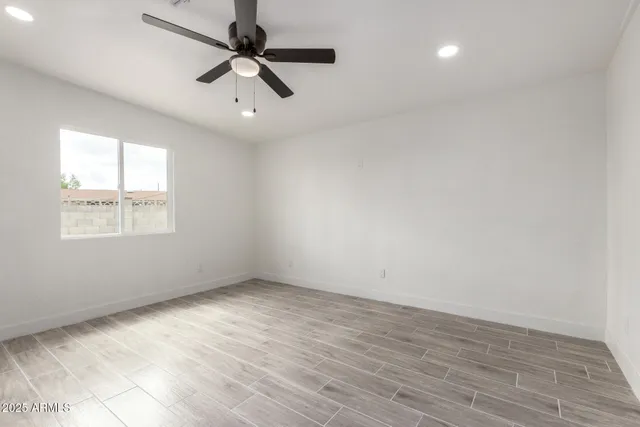an empty room with wooden floor ceiling fan and windows