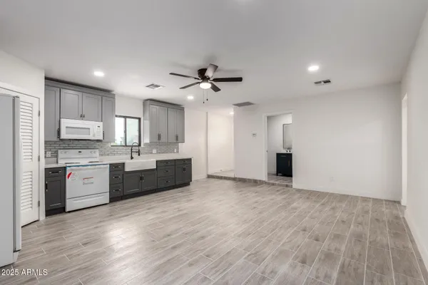 a large kitchen with stainless steel appliances granite countertop a stove a sink and white cabinets with wooden floor