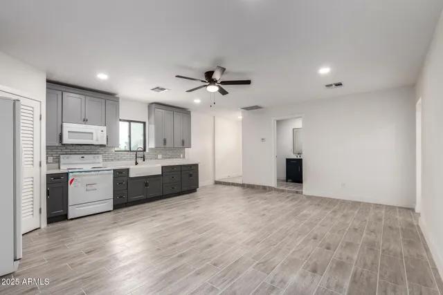 a large kitchen with stainless steel appliances granite countertop a stove a sink and white cabinets with wooden floor