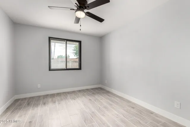 an empty room with a window and ceiling fan
