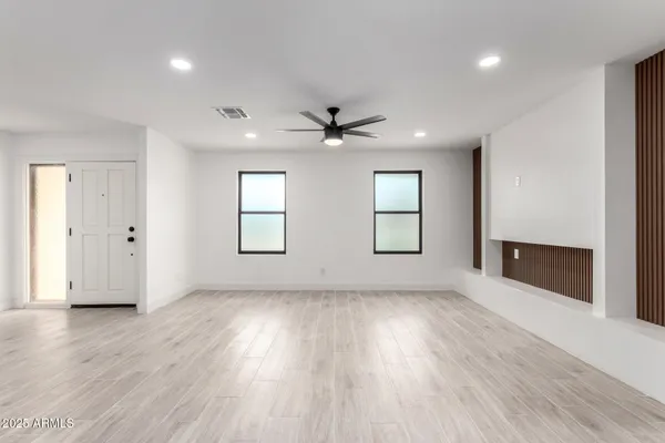 an empty room with wooden floor and windows