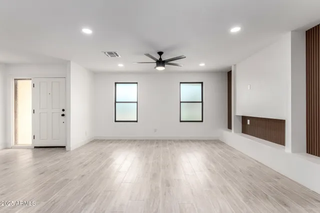 an empty room with wooden floor and windows