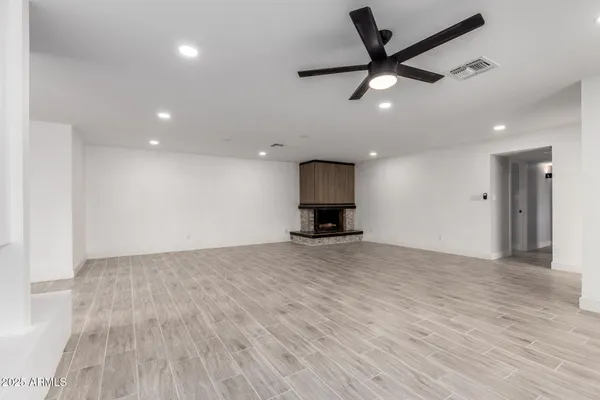 a view of empty room with wooden floor and a ceiling fan