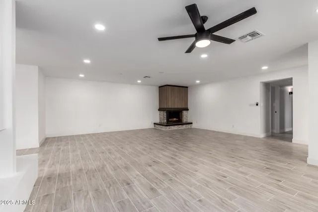 a view of empty room with wooden floor and a ceiling fan