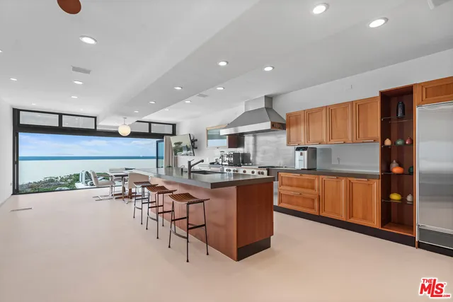 a kitchen with stainless steel appliances kitchen island granite countertop a table and chairs in it