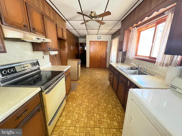 a kitchen with stainless steel appliances granite countertop a sink a stove cabinets counter space and a window