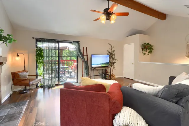 a living room with furniture a ceiling fan a fireplace and a large window