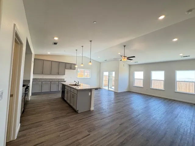 a large kitchen with granite countertop a large counter top stainless steel appliances and windows